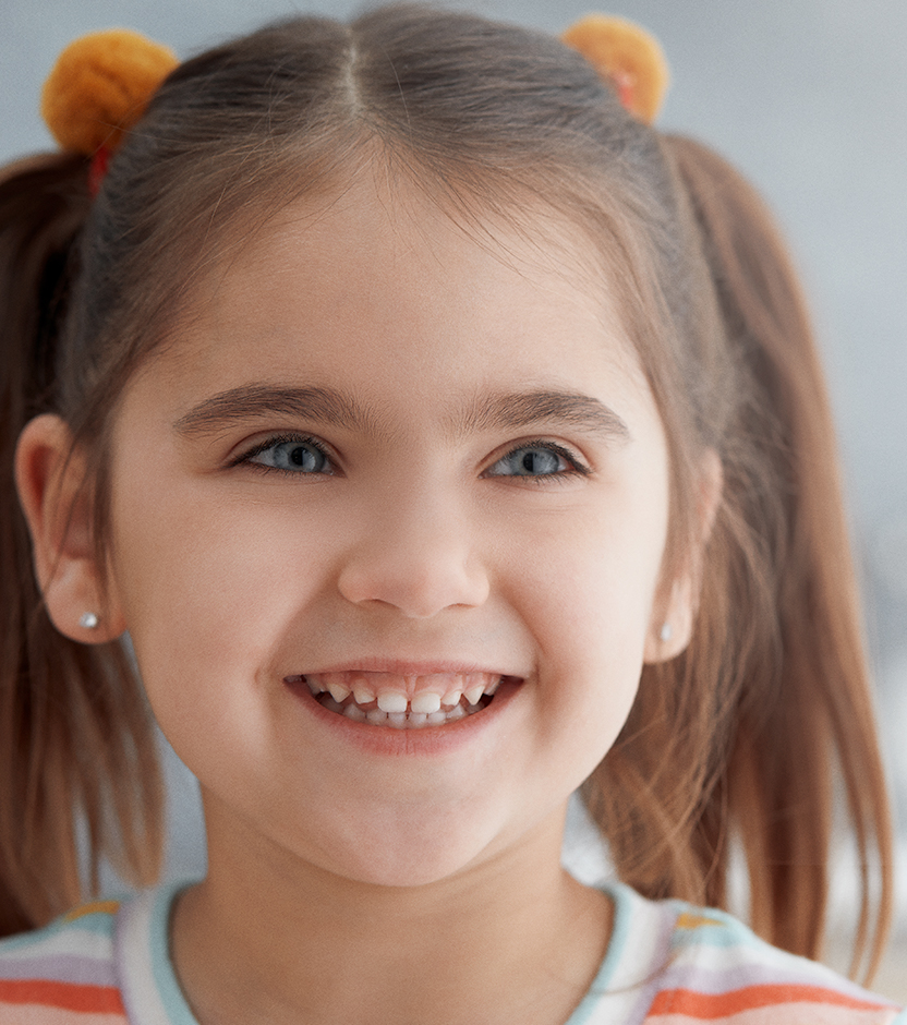 A young girl with pig tails smiles in a primary care office setting 